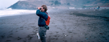 A person on a beach looking through binoculars.