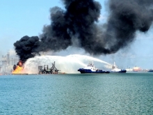 Smoke billowing from an explosion with water being sprayed at the fire.