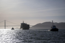 Several vessels in water with a bridge in the background.