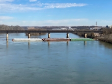 Overturned barges in water near a bridge. 