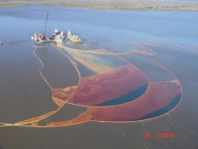 A sheen with colors of black, red, and yellow in a body of water. 