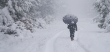 A person with an umbrella walking through snow.