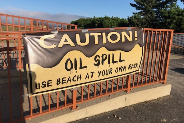 A sign reading "Caution: Oil Spill." 