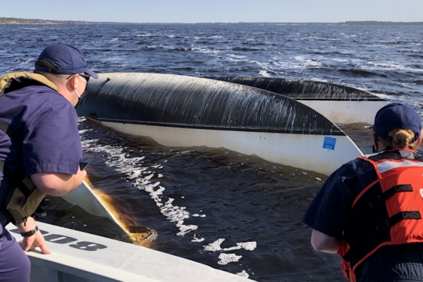 Two people pulling in an overturned boat.