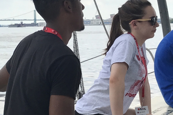 Two people sit on the port side of the sailboat.