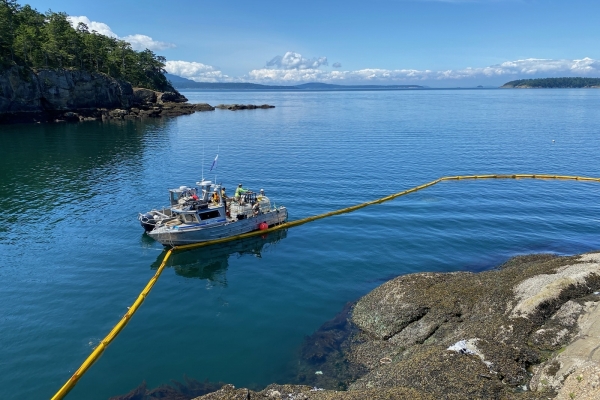 Pollution boom around a rocky shoreline.