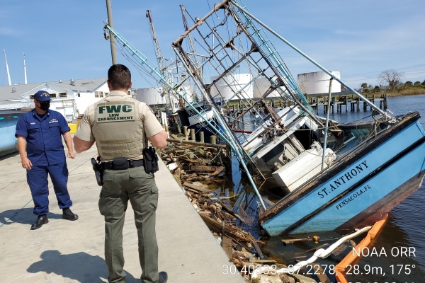 Two people on a dock looking at displaced vessels. 