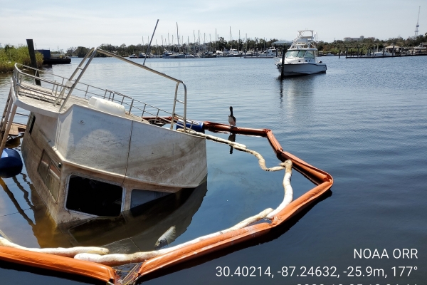 A sinking vessel surrounded by pollution boom.
