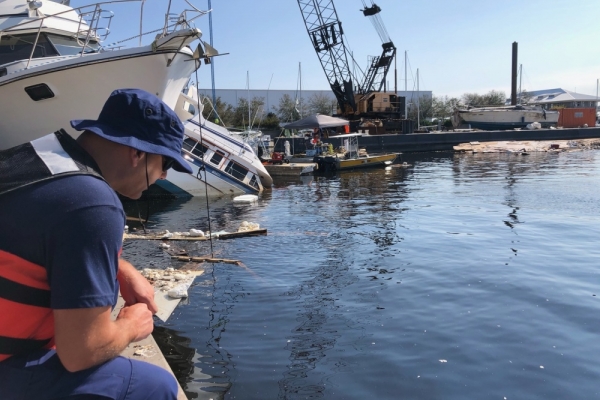 A person crouching at a dock. 