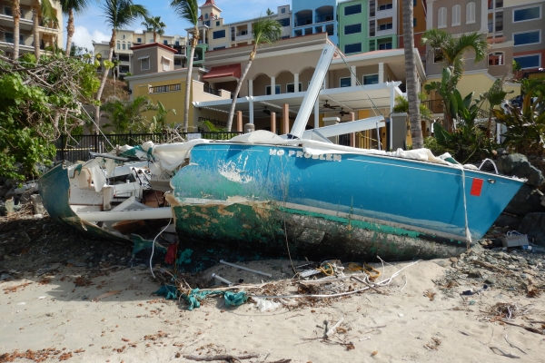 A grounded vessel on a beach with buildings in the background. 